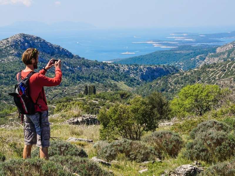 male hiker taking a view of Croata's landscape and the Adriatic Sea