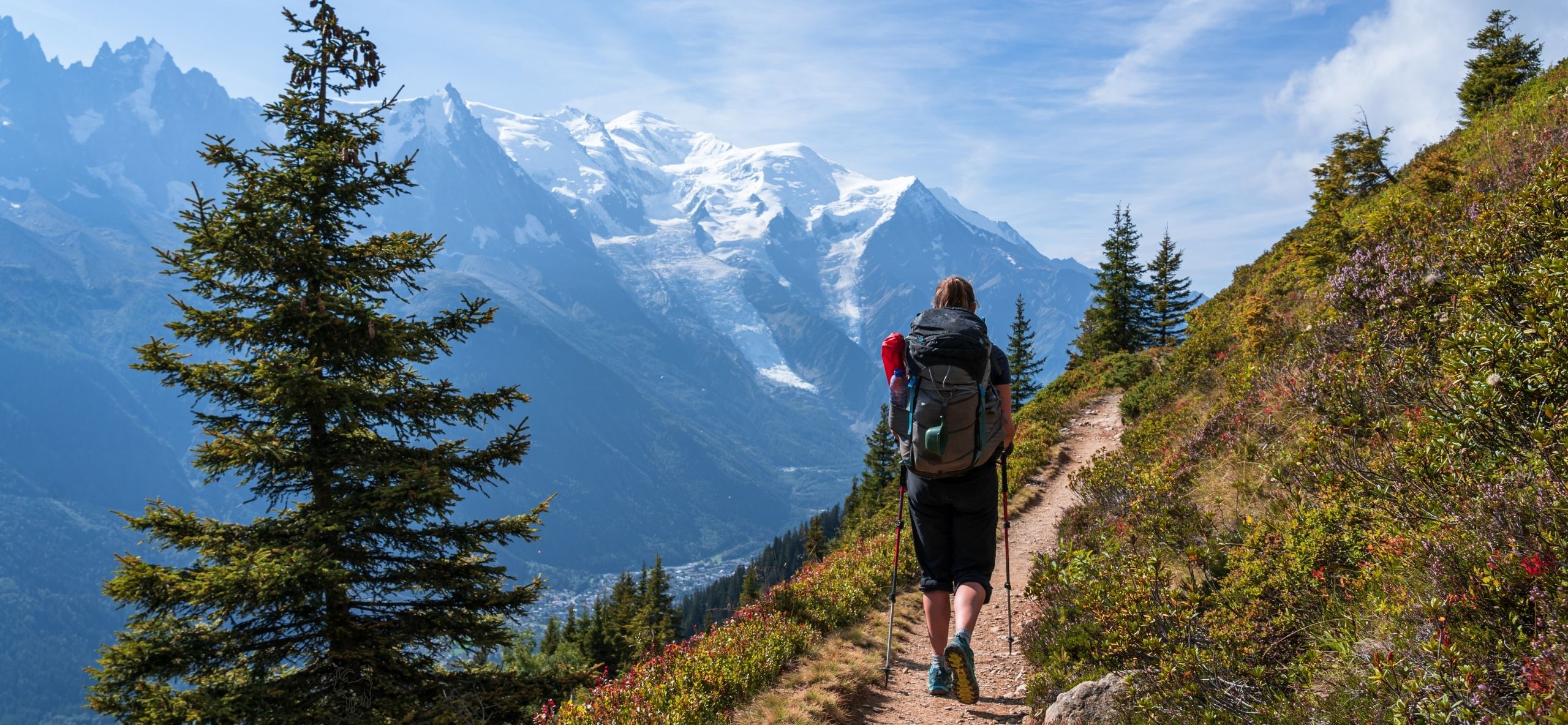 Hiker with a backpack walking a mountain trail toward Mont Blanc on the Tour du Mont Blanc self-guided hiking tour