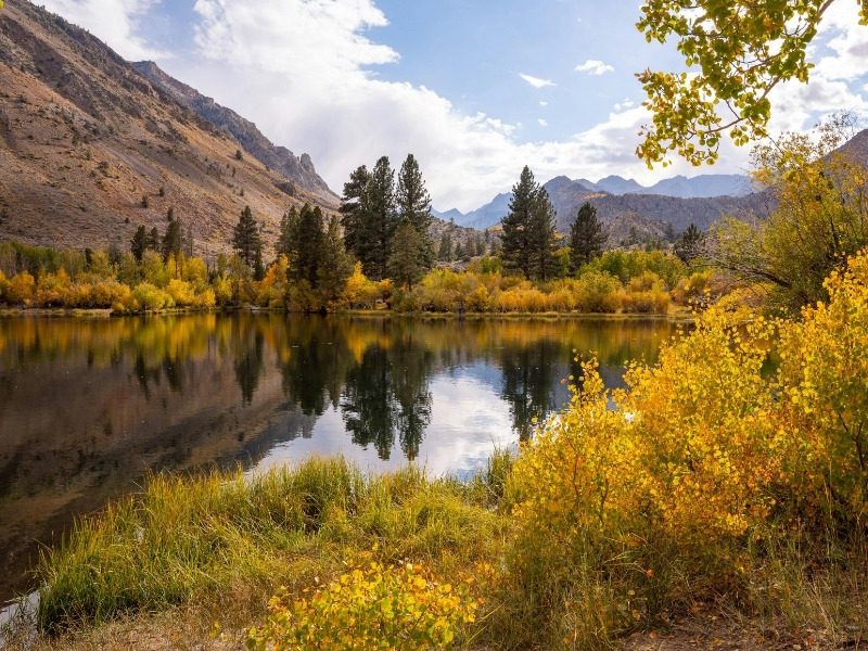 Fall color reflected in a still mountain pond below the peaks on a hiking trip in southern Spain