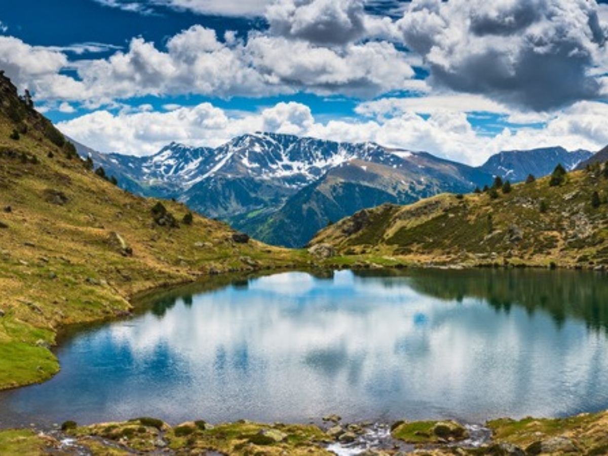Snow-streaked peaks reflected in a still high mountain lake in Andorra