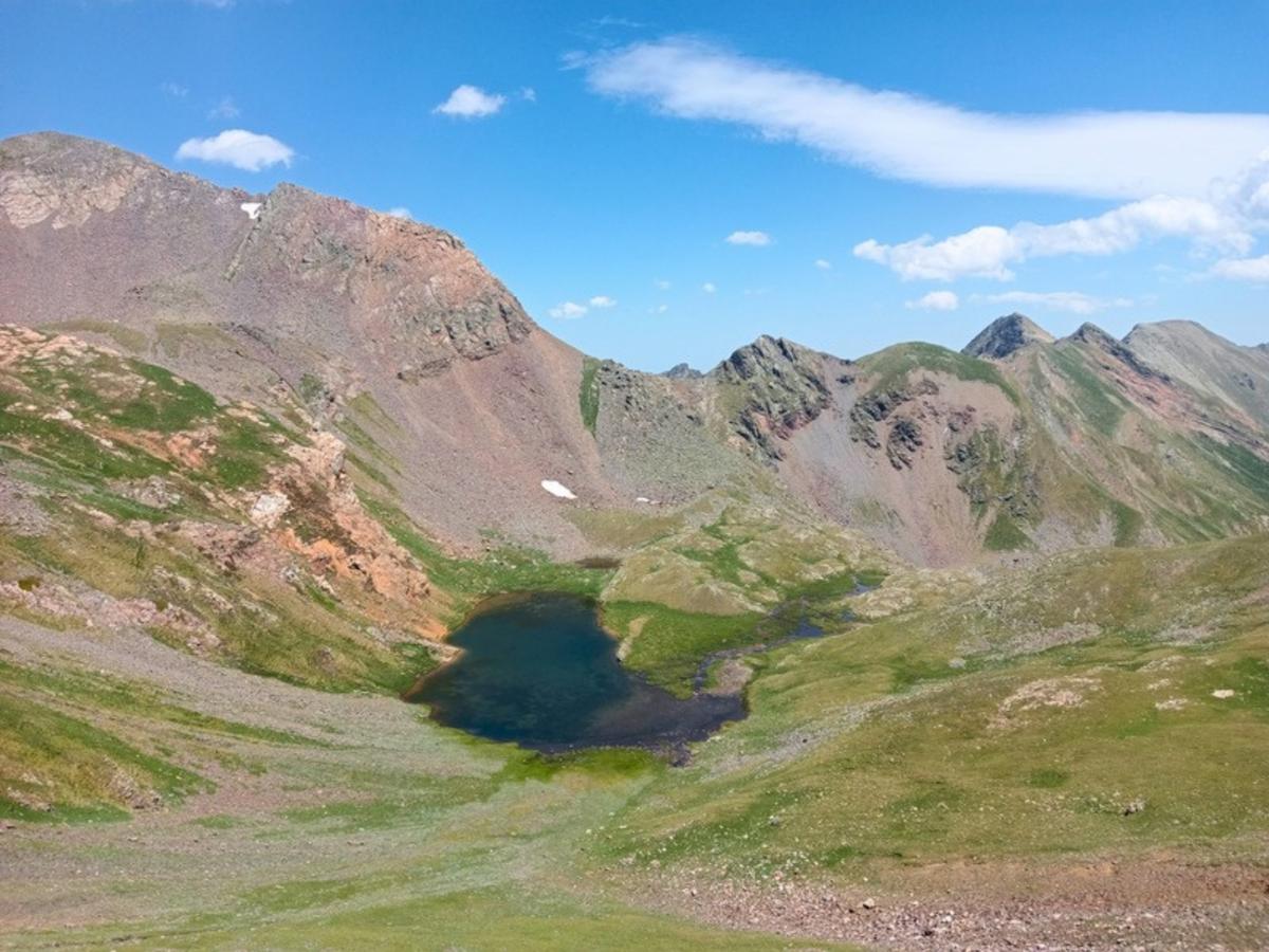 A small dark lake in a wide glacial cirque on an Andorra hiking tour