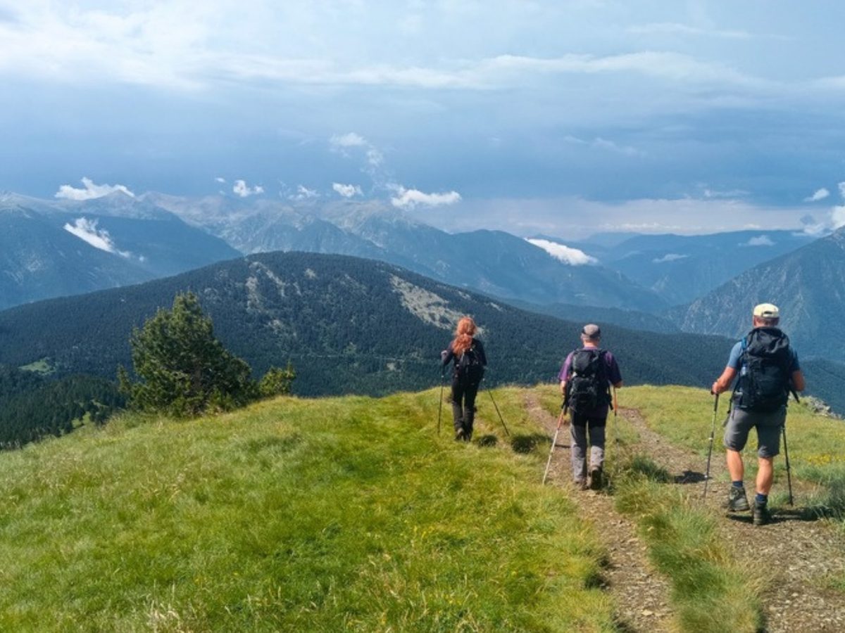 Three hikers with poles on a grassy ridge trail on a self-guided Andorra hiking tour