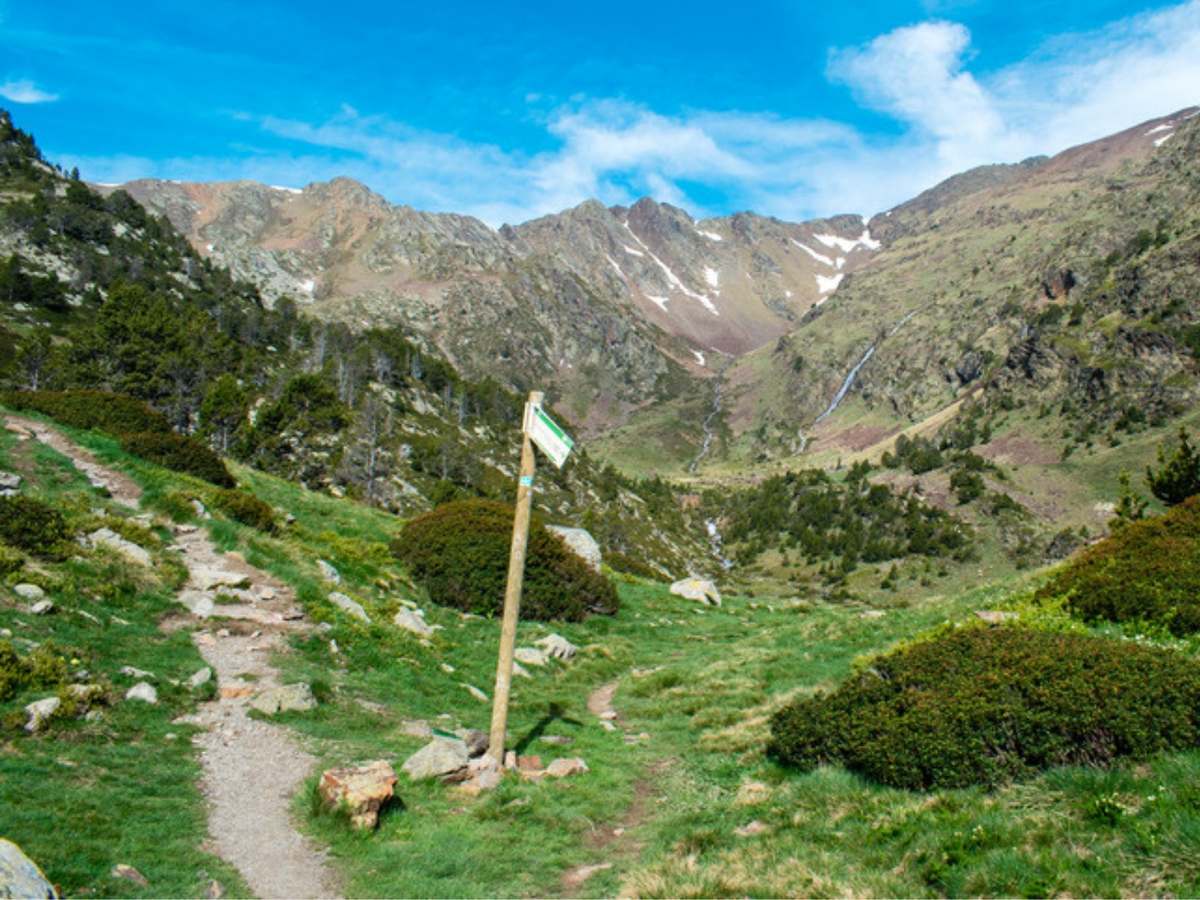 A waymarked signpost on a hiking trail in Andorra with the Pyrenees behind