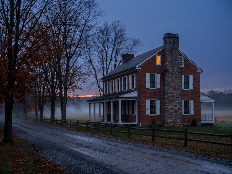 Haunted hotels in Gettysburg - a historic brick inn at dusk with mist across the fields