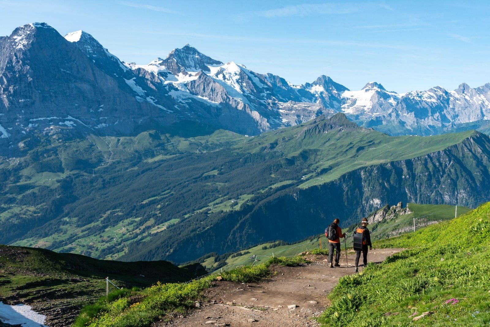 two hikers on a trail above Grindelwald in the Swiss Alps with the Eiger behind them