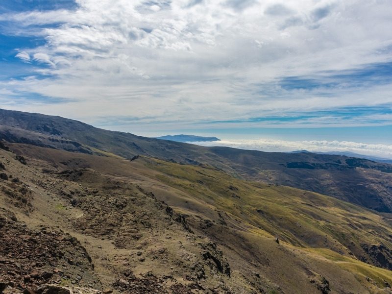 A hiking trail across the high open pastures of the Sierra Nevada with a sea of cloud on the horizon
