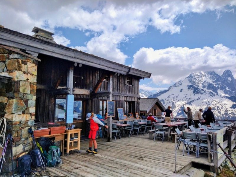 Hiker on the sunny terrace of Refuge du Lac Blanc on the Tour du Mont Blanc
