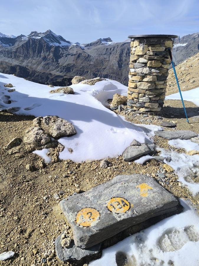 Yellow Alta Via 2 waymarks painted on rock beside the stone marker at the Col Rosset, Gran Paradiso National Park