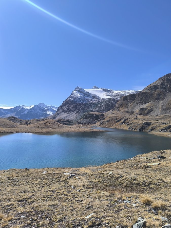 A deep blue glacial lake below rocky peaks on the Gran Paradiso hiking tour in the Italian Alps