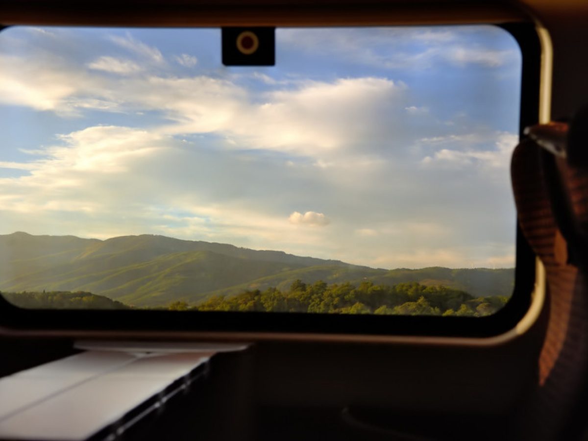 Green hills seen through the window of an Italian train heading north to the Dolomites