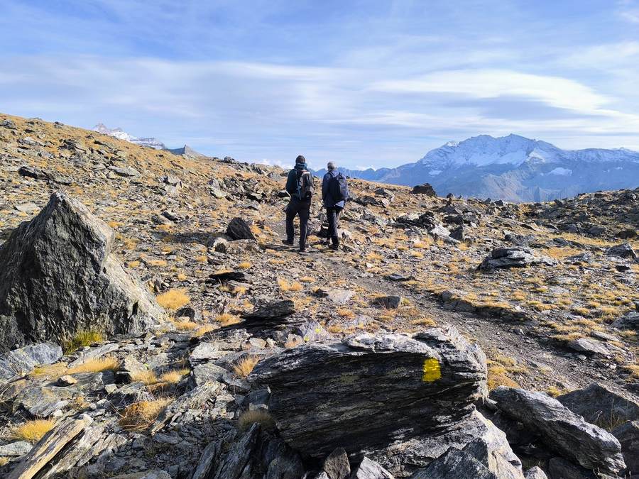Hikers on the rocky trail below the Col Rosset on the Gran Paradiso hiking tour in the Italian Alps