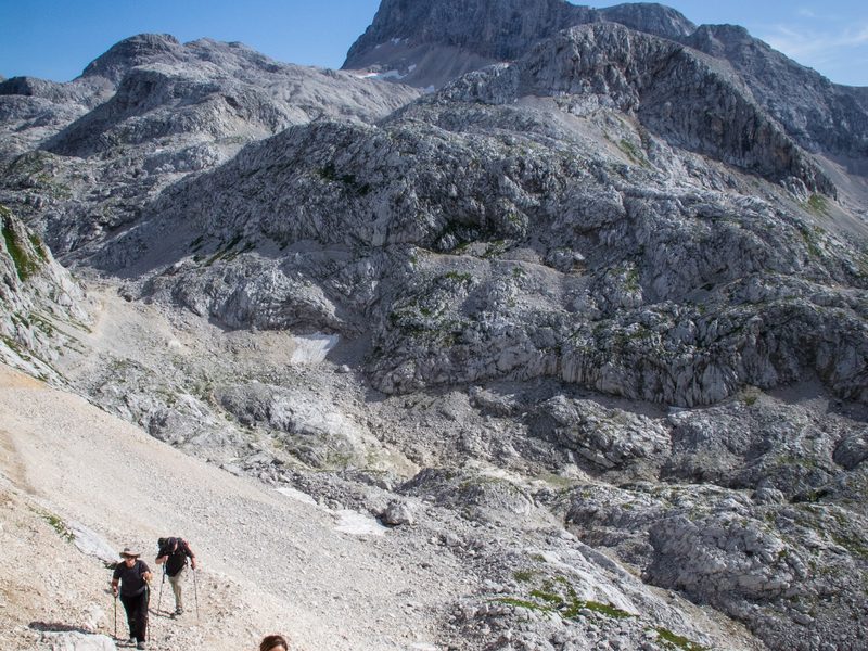 Hikers descending below a julian alps peak
