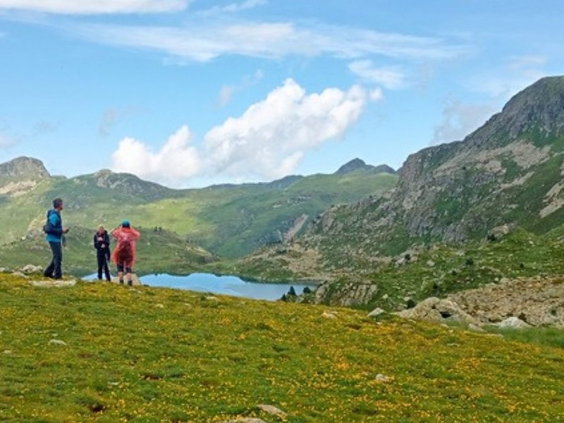 Three hikers above a high mountain lake while hiking in Andorra, on the border with Spain