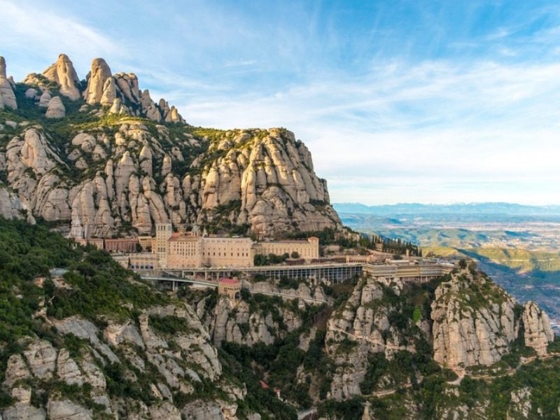 Hiking Montserrat from Barcelona: the monastery on its ledge below the rock towers of the massif