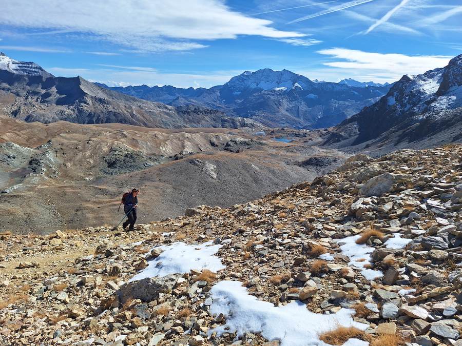 A hiker crossing open scree below the Col Rosset on the Gran Paradiso hiking tour