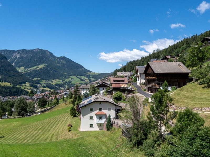 Chalet-style hotels on the green hillside above Ortisei in Val Gardena, Dolomites, Italy