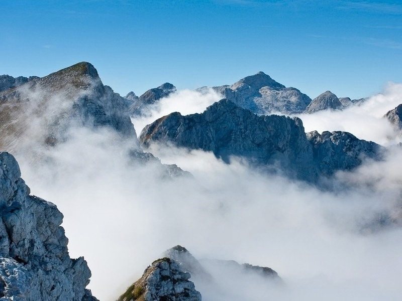 Jagged limestone peaks of the Julian Alps rising out of low cloud, the view from the high huts on the Slovenia hut to hut hike