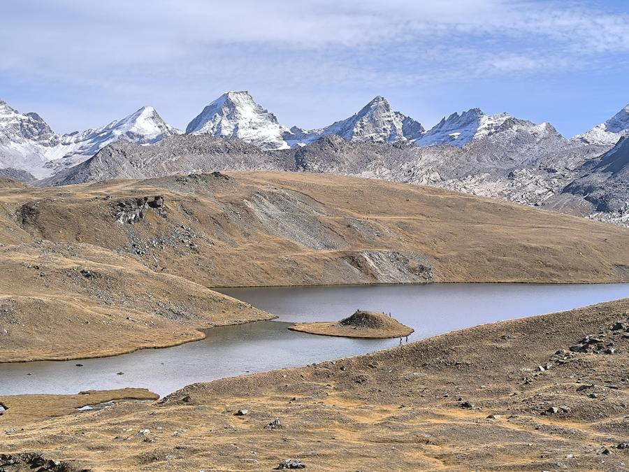 Lago Rosset and its island below snow-capped peaks in Gran Paradiso National Park, Italian Alps