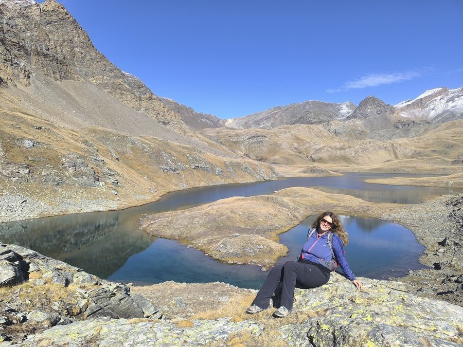 Laurel Robbins of Monkeys and Mountains sitting on rock above Lago Leita on the Gran Paradiso hiking tour