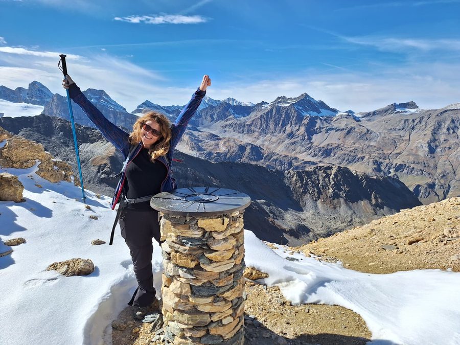 Laurel Robbins of Monkeys and Mountains with her arms raised at the Col Rosset on the Gran Paradiso hiking tour in the Italian Alps