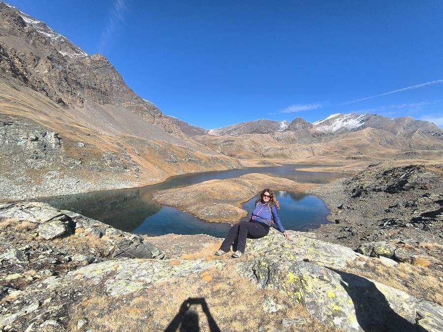 A hiker resting on rock above the linked lakes of the Plan del Nivolet, Gran Paradiso National Park