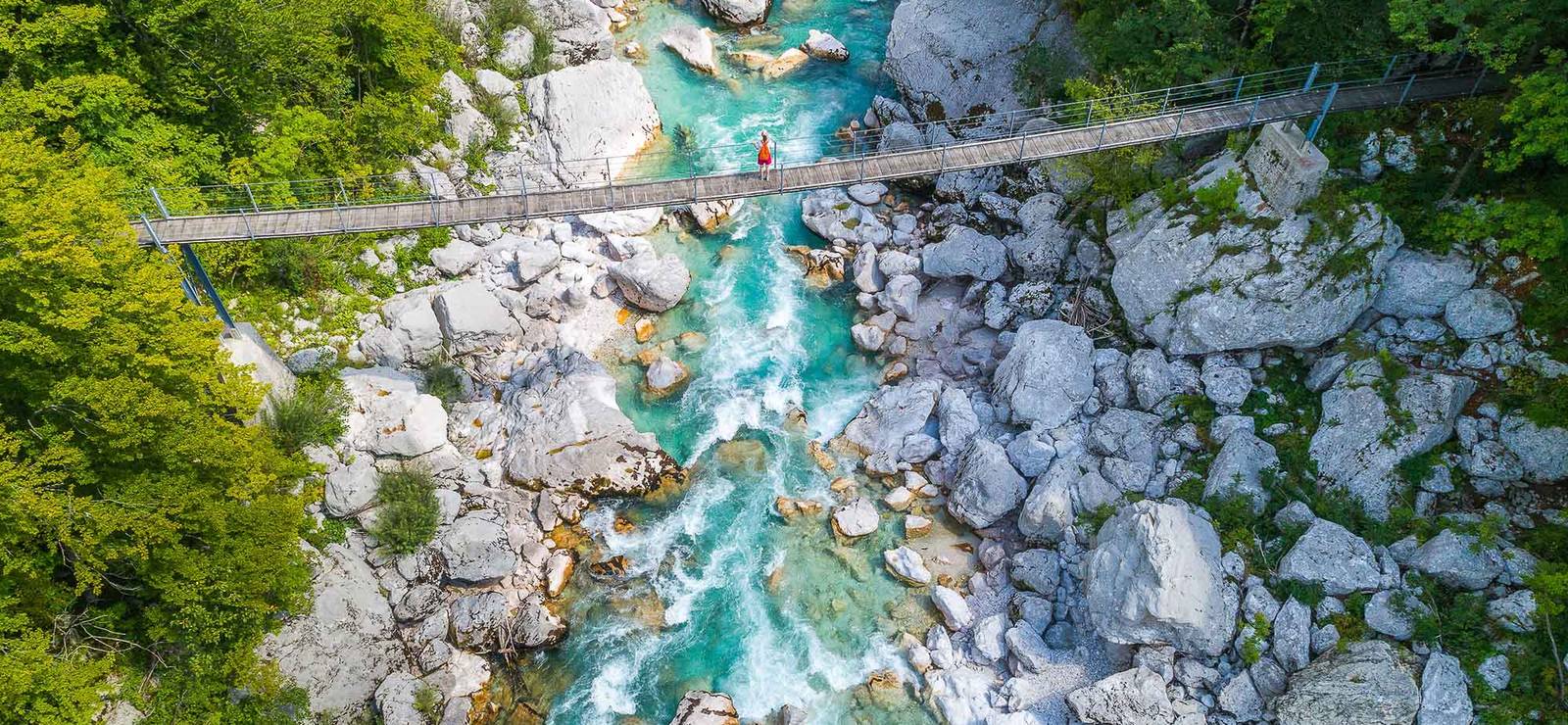 A hanging bridge over the emerald Soča River on the Juliana Trail in Slovenia, one of the best hikes in Europe