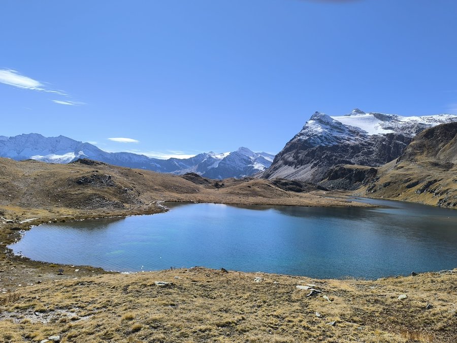 A turquoise glacial lake below snow-streaked peaks in Gran Paradiso National Park, Italian Alps