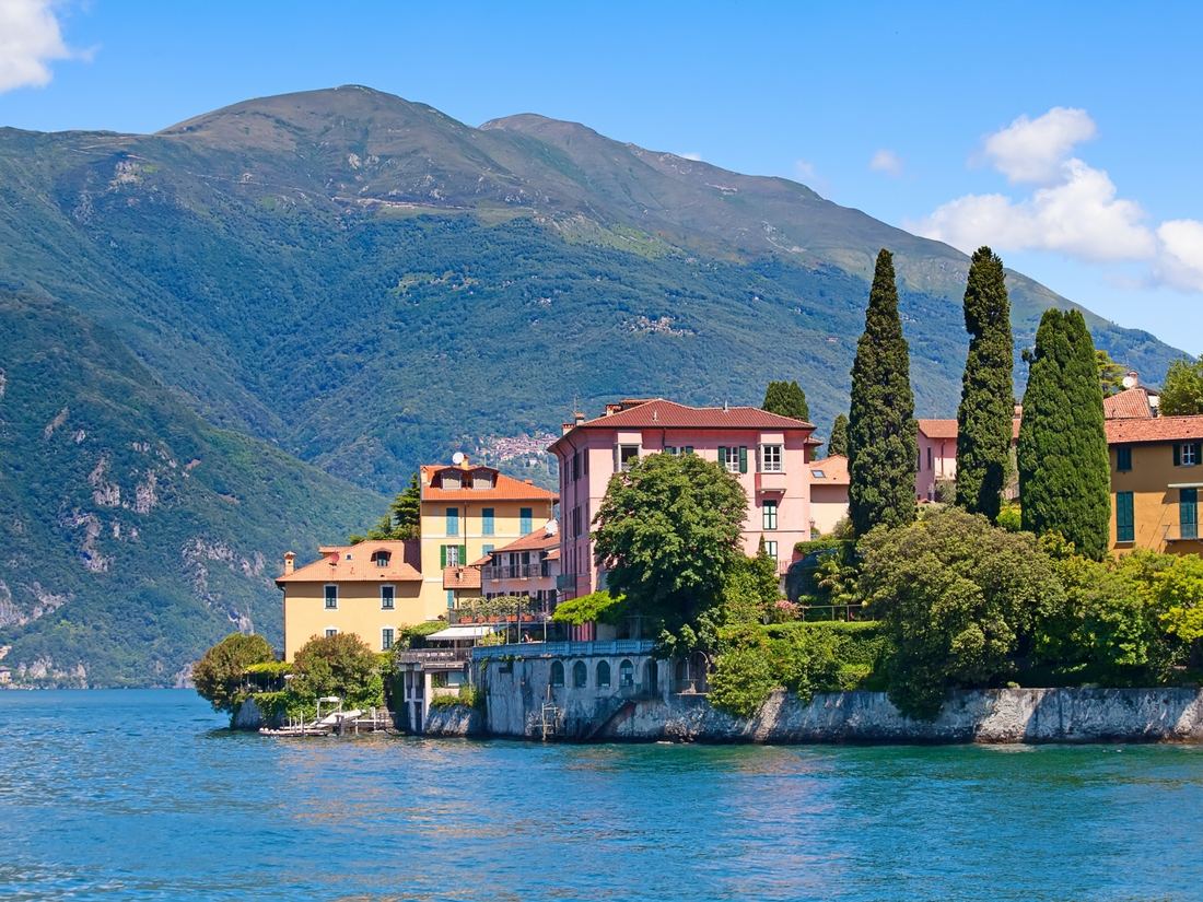 A villa and cypress trees on a rocky point, the kind of setting that decides where to stay in Lake Como, Italy